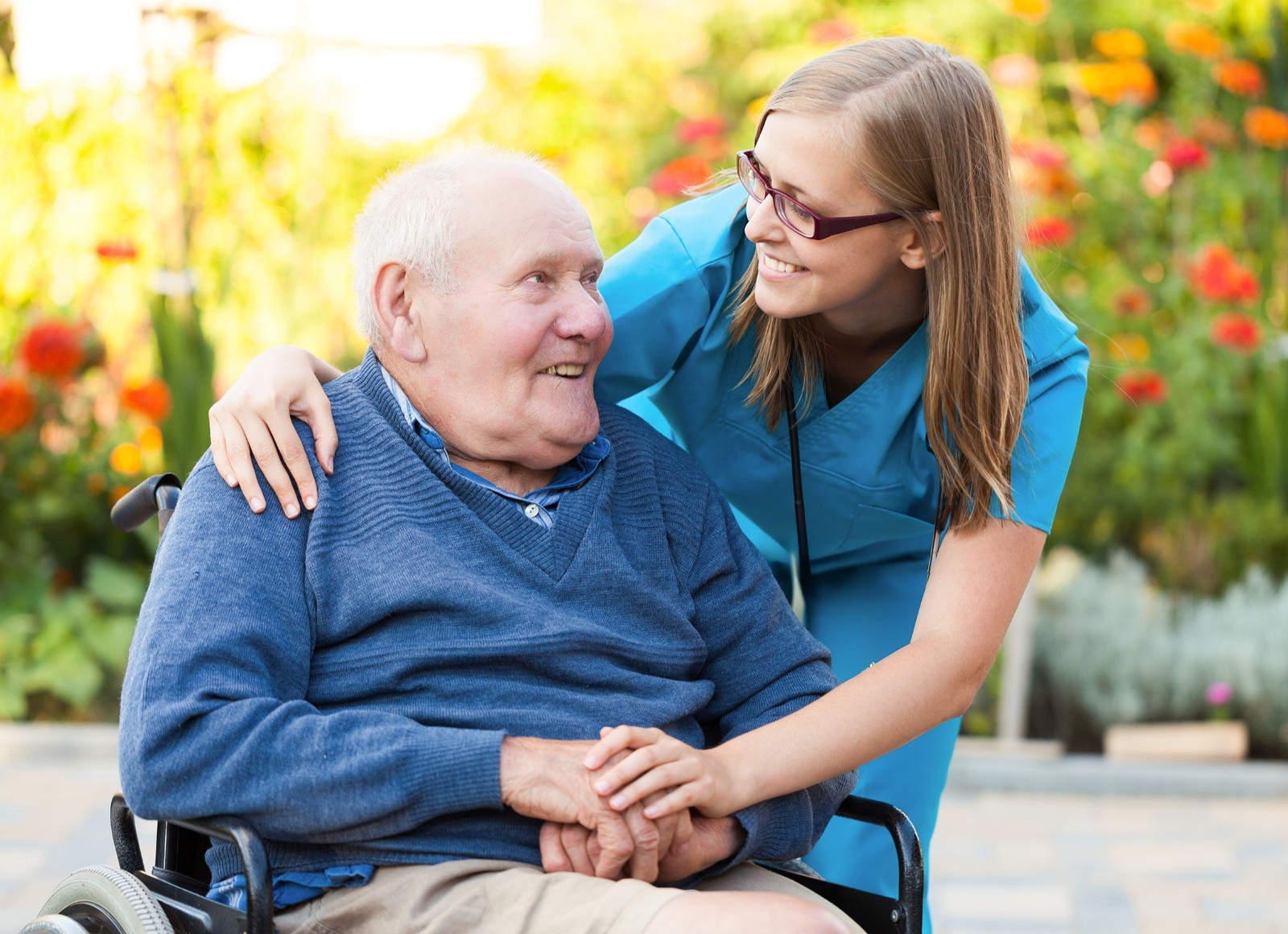 Two people smiling at each other. One is stood and has their arm around the other in a reassuring manner.